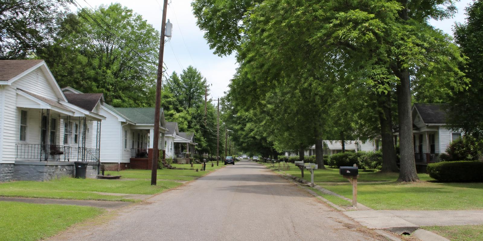 A tree-lined residential street of older single-family homes in a small North Alabama town